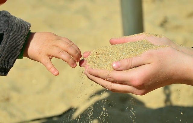 Kinderhände lassen Sand durch die Finger rieseln