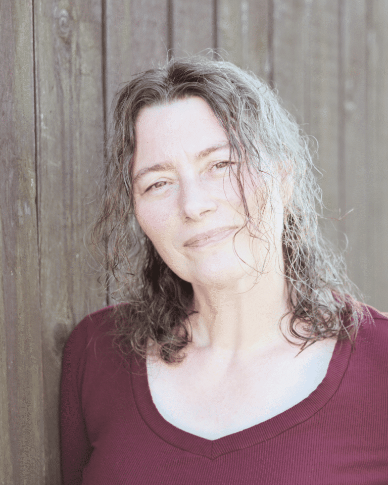 Sandra Quedenbaum, coach for highly sensitive people, portrait in front of a wooden wall