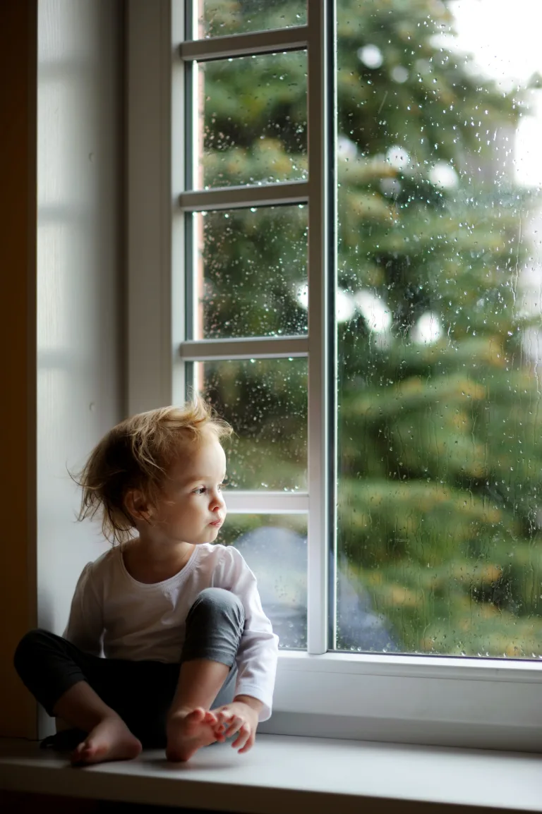 Hochsensibles Kind sitzt am Fenster und schaut still hinaus