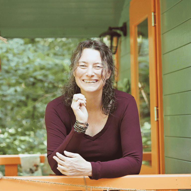 Sandra Quedenbaum laughing on a porch surrounded by greenery