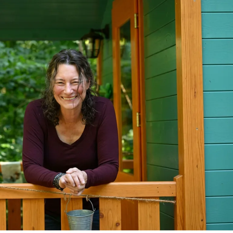 Sandra Quedenbaum, Ausbilderin für HSP Coaches, lachend auf ihrer Veranda im Grünen
