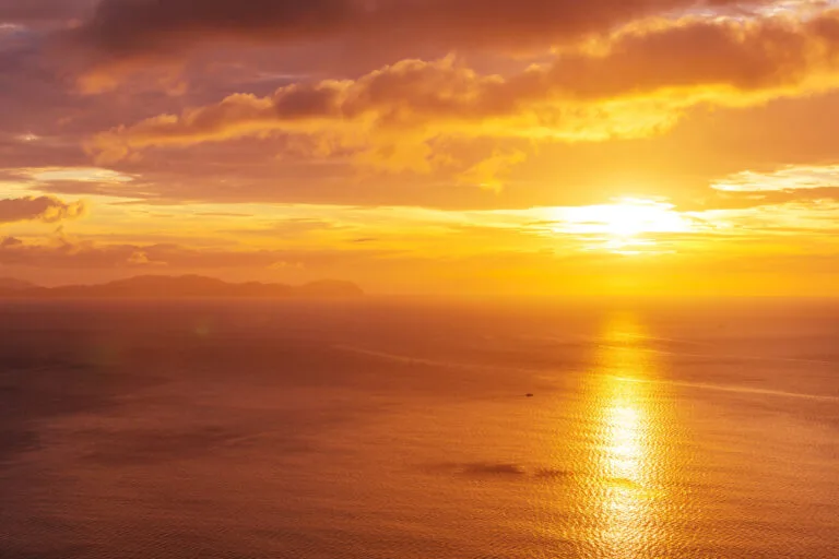 Sonnenuntergang über dem Meer, das goldene Licht spiegelt sich ruhig auf dem Wasser